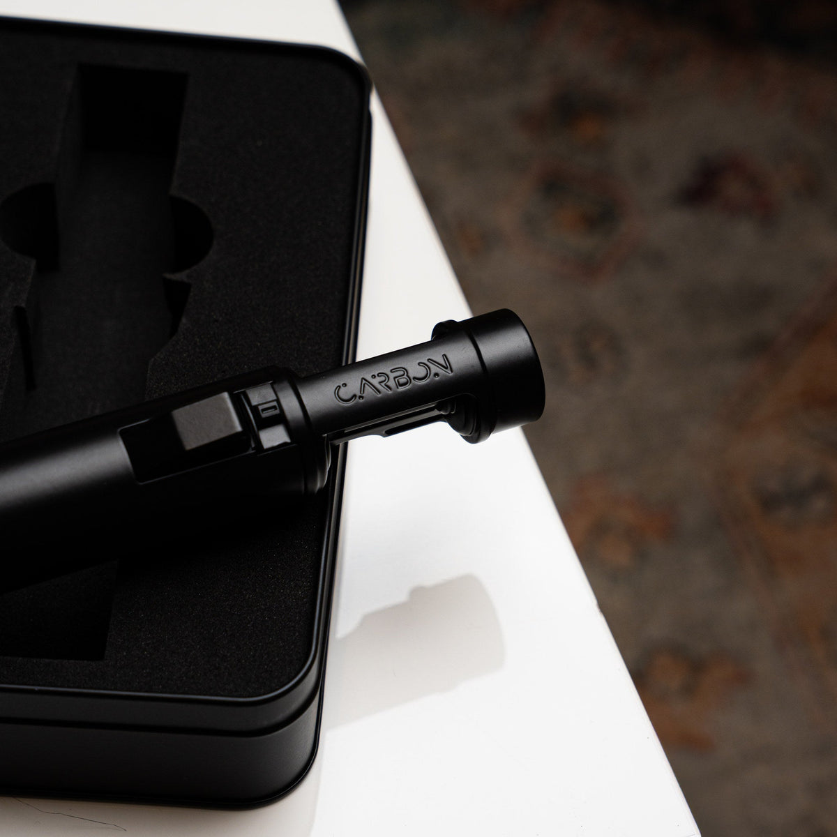 Carbon Ignis torch lighter resting on its case