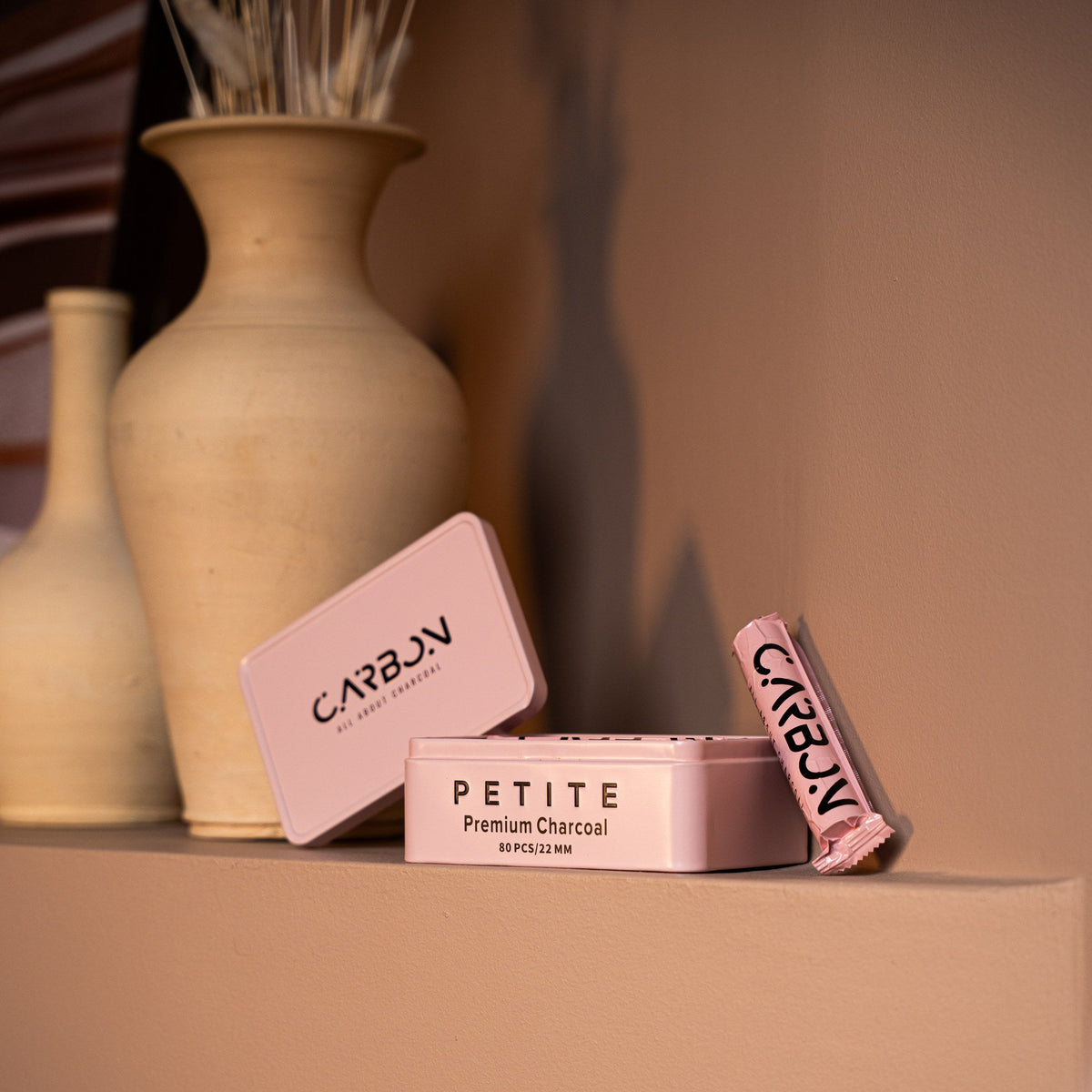 Carbon Petite tin and roll on a shelf beside ceramic vases