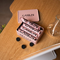 Carbon Petite tin filled with charcoal rolls, lid beside it