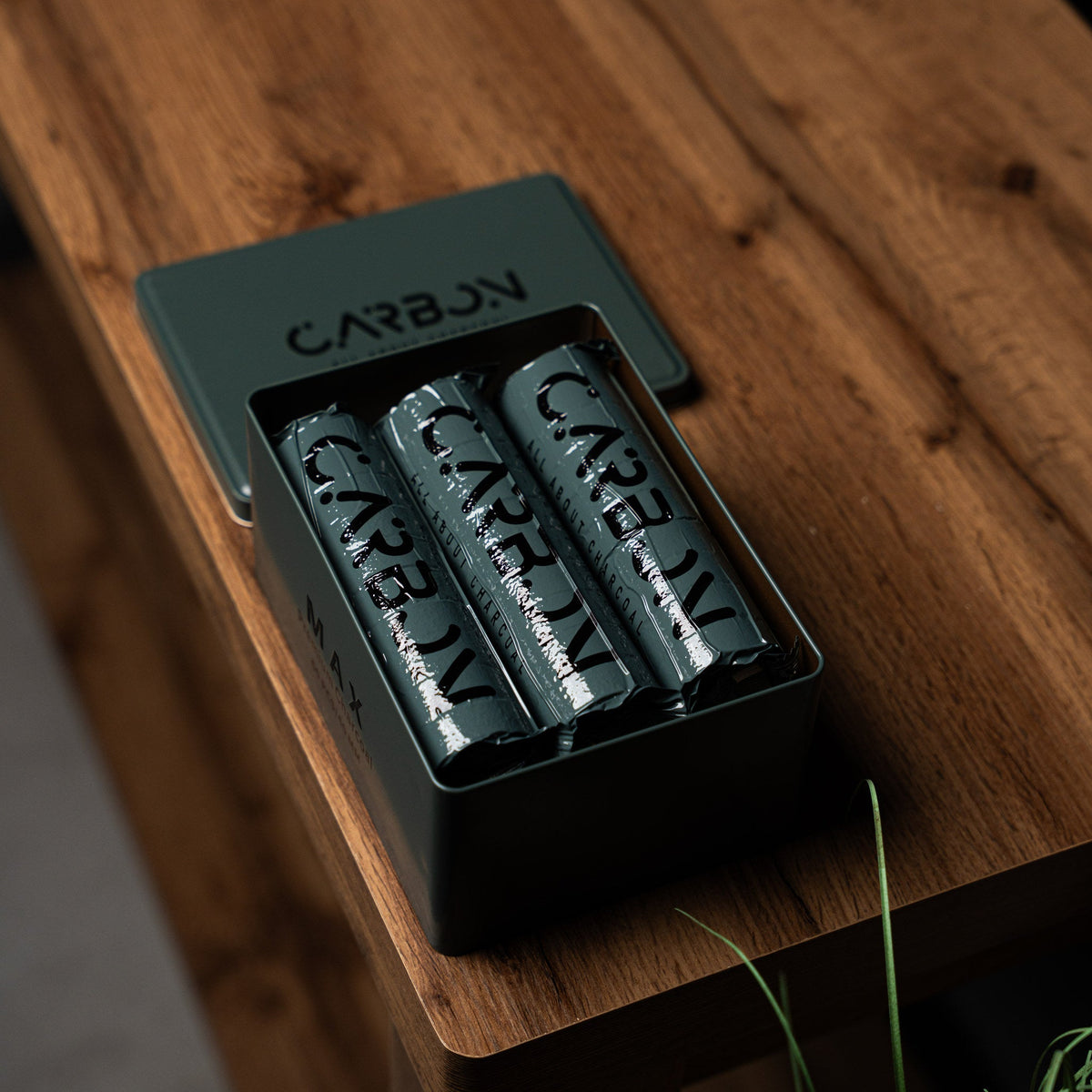 Carbon Max charcoal rolls in an open tin on a wooden table