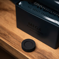Carbon Mega tin with a charcoal piece on a wooden table