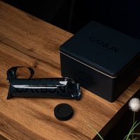 Carbon Mega tin, roll and a charcoal piece on a wooden side table